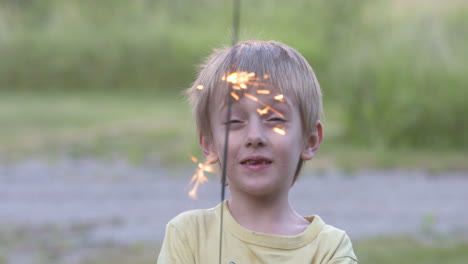 Happy-little-boy-playing-with-a-sparkler-on-a-summer-evening