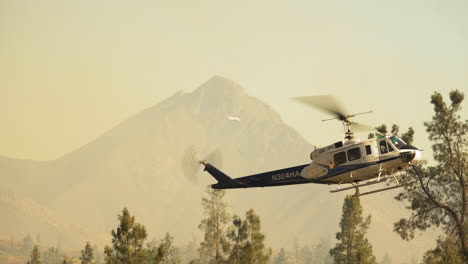 Emergency-helicopter-with-water-bucket-monitoring-California-bush-fire