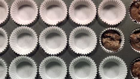 overhead-time-lapse-ladling-chocolate-batter-into-muffin-cups-and-adding-chocolate-chips-to-top