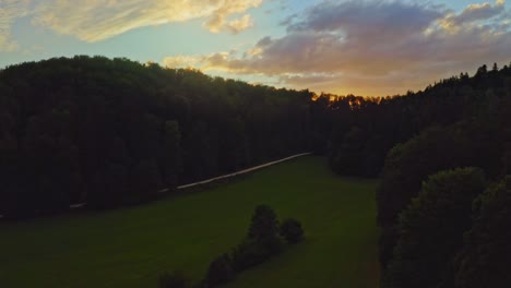 Sunset-over-the-trees-at-recreation-area-og-the-Swabian-Alb-while-the-sunbeams-are-getting-discovered-by-the-uprising-drone-flight