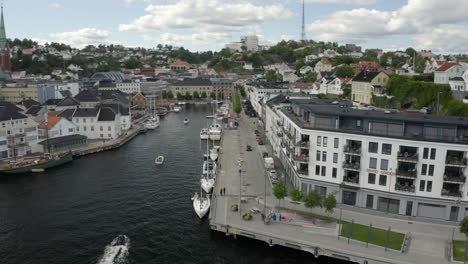 Boats-Moored-At-The-Pollen-Harbour-With-The-Grand-Garden-Building-In-Langbryggen,-Arendal,-Norway