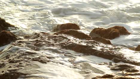 Sea-waves-splashing-on-rocks-at-the-beach-during-sunset