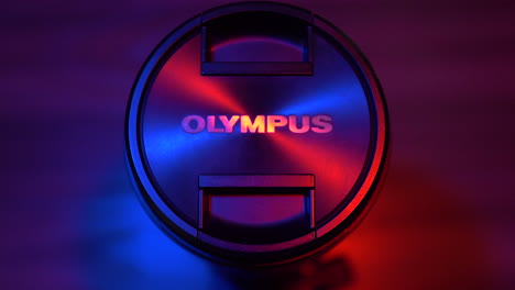 Statische-Aufnahme-Des-Olympus-Objektivdeckels-Mit-Filmischer-Roter-Und-Blauer-Beleuchtung