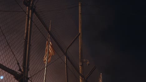 Amerikanische-Flagge-Weht-Nachts-Hinter-Einem-Zaun,-Umgeben-Von-Rauch