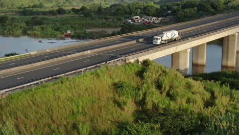 Toma-De-Drones-En-Aumento-De-Un-Solo-Camión-De-Cemento-Que-Conduce-Sobre-El-Puente-De-La-Autopista-Umzimkhulu-En-Port-Shepstone,-Sudáfrica