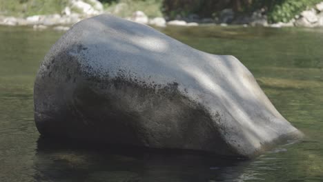 Large-boulder-in-a-still-river-with-dappled-sunlight