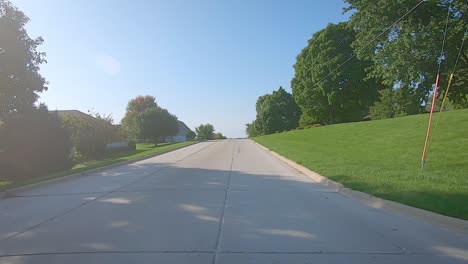 POV-of-an-approaching-Amish-horse-and-buckboard-wagon-while-waiting-at-a-stop-sign-in-small-town---Kalona,-Iowa