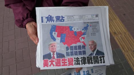 Una-Mujer-Distribuye-Un-Periódico-En-Chino-Que-Presenta-En-Su-Portada-La-Carrera-Presidencial-Estadounidense-Entre-El-Actual-Presidente-Donald-J