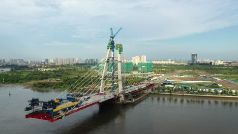 aerial-tracking-shot-flying-past-Thu-Thiem-Two-Bridge-under-construction-with-view-of-Saigon-River