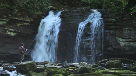 A-fisherman-catches-a-small-fish-below-Seneca-Falls,-a-large-waterfall-located-along-Seneca-Creek,-within-the-Spruce-Knob-Seneca-Rocks-National-Recreation-Area-in-West-Virginia