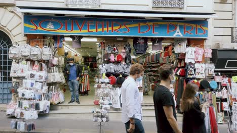 Aufnahme-Eines-Souvenirladens-In-Der-Montmartre-Straße-Mit-Touristen,-Die-Aufgrund-Einer-Coronavirus-Pandemie-Eine-Maske-Tragen,-Paris,-Frankreich