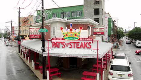 Pat's-King-of-Steaks,-famous-Philly-cheesesteak-location,-aerial-push-in-shot,-famous-worldwide-by-tourists-for-iconic-sandwich