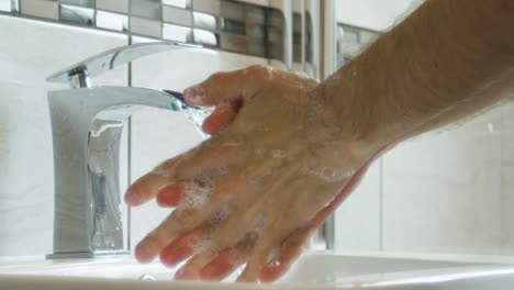 Ein-Mann-Spült-Seife-Von-Händen-Und-Armen-In-Einem-Waschbecken-Im-Badezimmer,-Nahaufnahme-In-Superzeitlupe