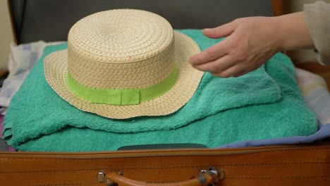 Hand-unpacking-straw-hat-from-suitcase-close-up-shot