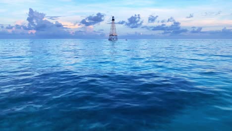 Clip-of-the-ocean-and-calm-blue-water-witha-a-lighthouse-in-the-background-in-Alligator-Reef-Light-in-Florida-keys