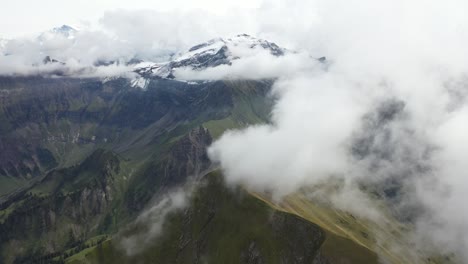 Drone-shot-over-Morgenberghorn-flying-sideways-slowly-over-the-beautiful-and-green-landscape-of-Switzerland-amongst-the-clouds