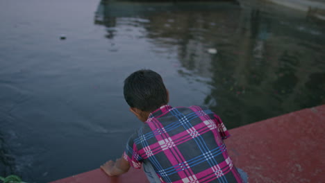 A-boy-approaches-a-river-with-a-lit-candle-and-moves-to-place-it-in-the-water