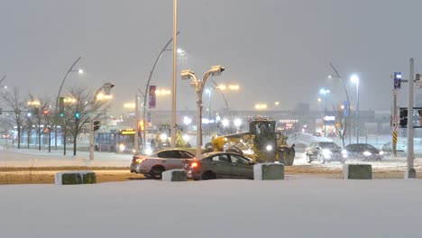 Parade-Von-Pistenfahrzeugen,-Die-Schnee-Räumen,-Während-Sie-An-Einer-Belebten-Straßenecke-Abbiegen