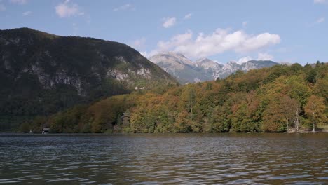 Bohinjer-See-Mit-Wunderschönen-Herbstfarben-Und-Sich-Schnell-Bewegenden-Wolken,-Die-Die-Bäume-Erhellen,-Mit-Dem-Triglav-Nationalpark-Im-Hintergrund