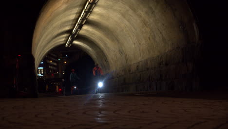 Cyclists-ride-through-the-illuminated-passage-during-the-night