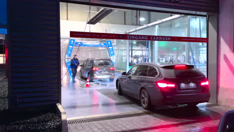 Static-wide-shot-of-worker-preparing-and-spraying-car-in-carwash-hall
