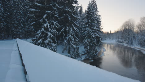 Pan-of-river-and-forest-from-bridge-in-snowy-wintertime-Finland
