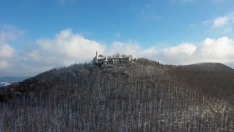 Aerial-flying-towards-medieval-Castle-Teck-on-a-mountain-on-a-snowy-day-during-winter-in-Swabia,-Germany