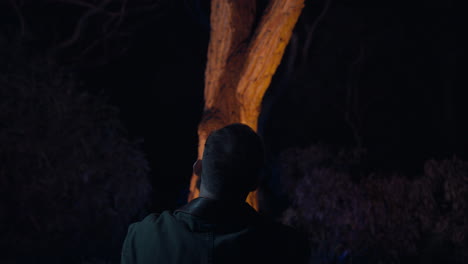 Lumber-jack-sits-in-front-of-a-glowing-tree-in-the-bush-at-night