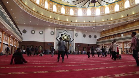 Muslim-People-Walking-On-Carpeted-Floor-Inside-Islamic-Center-Mosque-In-Mataram,-Lombok-With-Elegant-Ceiling---low-level,-wide-shot