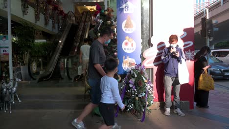 People-wearing-face-masks-walk-past-a-flower-and-home-deco-products-shop-with-a-Christmas-tree-and-ornaments-displayed-at-its-entrance-in-Hong-Kong