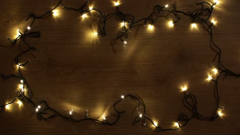 Christmas-lights-on-wooden-table-background,-copy-space