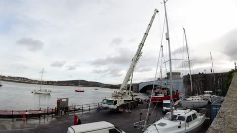 Hydraulic-crane-vehicle-lifting-fishing-boat-vessel-into-Conwy-harbour-marina-timelapse