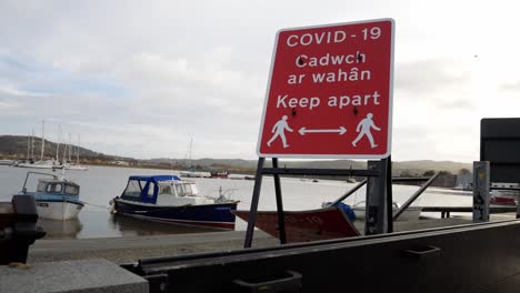 Red-Welsh-Conwy-council-covid-social-distance-sign-on-harbour-coastline-jub-up