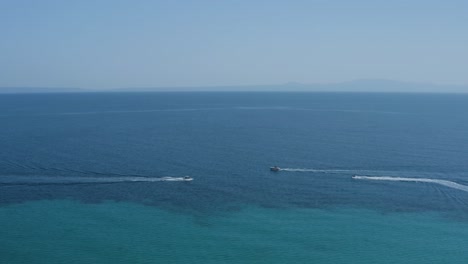 Aerial-slide-left-shot-of-boats-and-jet-ski-pass-by-in-dark-blue-sea
