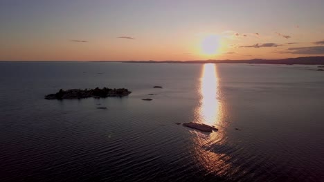 Small-Rocky-Islands-in-Big-Blue-Lake-at-Sunset,-Drone-Aerial-Wide-Dolly-In