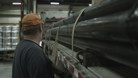 American-truck-driver-securing-a-load-of-pipes-on-his-flatbed-trailer-stabilized-slider-shot