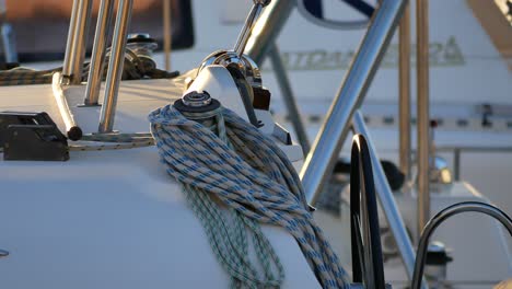 Una-Toma-Del-Timón-De-Un-Barco-Con-Cuerdas-Enrolladas-Cerca,-Balanceándose-Lentamente-Con-Las-Olas-En-Un-Muelle-Deportivo