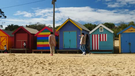 Tourists-walking-and-taking-photo-at-Brighton-Bathing-Boxes,-Melbourne,-Australia