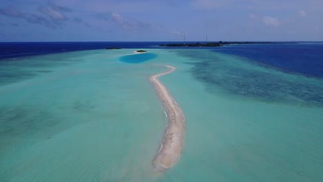 Long-sandy-dune-surrounded-by-shallow-turquoise-lagoon-with-clear-water-in-the-middle-of-Maldivian-archipelago,-deep-blue-ocean-horizon-under-purple-sky