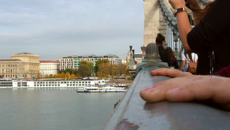 Close-up-of-hands-on-railing-of-bridge-over-river,-Budapest,-static