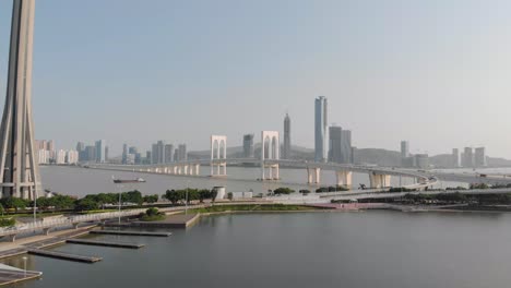 Drone-approach-shot-of-traffic-crossing-Sai-Van-Bridge-in-Macau-and-base-of-Macau-Tower