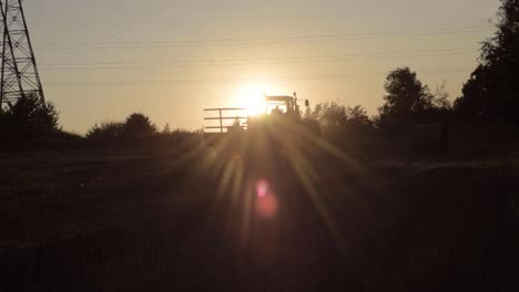 Silhouette-Eines-Bauern,-Der-Bei-Sonnenuntergang-Auf-Einen-Stationären-Traktor-Klettert