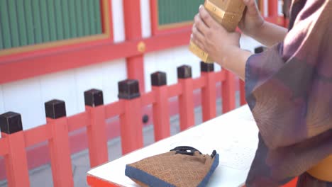 Guy-in-yukata-shaking-a-wooden-box-full-of-fortune-sticks-in-Kyoto,-Japan-soft-lighting-slow-motion-4K