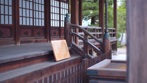 Traditional-wooden-pallet-with-ancient-Japanese-writing-on-it-sitting-on-the-steps-of-an-old-temple-in-Kyoto,-Japan-with-soft-lighting-4K