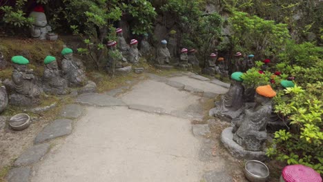 Small-Buddha-statues-with-woolly-hat-on-a-path-of-the-Daisho-in-Buddhist-temple-site-on-the-on-Miyajima-Island,-prefecture-of-Hiroshima