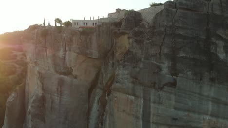 Cinematic-Drone-Shot-rising-over-Holy-Trinity-Monastry-during-Sunrise-in-Greece,-Meteora