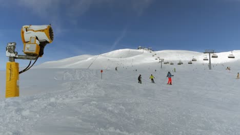 Cañón-De-Nieve-En-Las-Pistas-De-Esquí-Con-Ascensores-Y-Esquiadores-En-Un-Día-Soleado