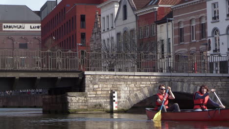 Adult-man-and-woman-canoeing-on-inner-city-river,-sunny-spring-day