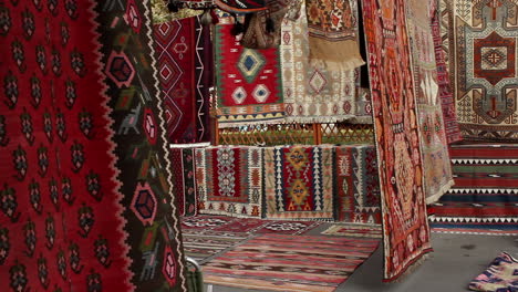Hanging-colourful-rugs-in-market-with-adult-male-walking-through-In-Yerevan,-Armenia