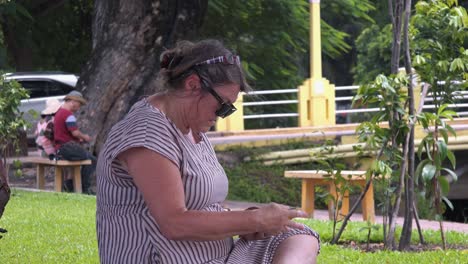 Western-Lady-Sitting-On-Bench-Looking-at-Postcards